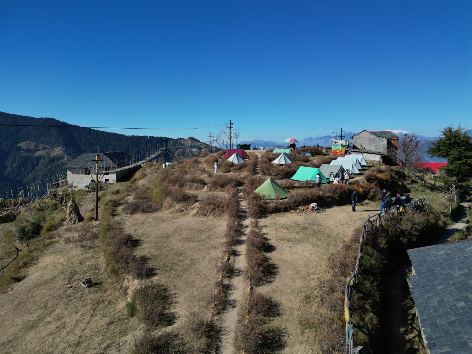 Ridge-top community campsite above the Khajjiar meadow with deep blue Himalayan sky, Chamba
